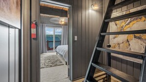 Een slaapkamer met een groot raam, een plafondventilator en uitzicht op een bos.