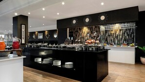 A modern kitchen with a central island, multiple serving stations, and a variety of food items. - Four Points By Sheraton Dar Es Salaam New Africa (Dar es Salaam)