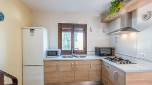 A compact kitchen with a refrigerator, microwave, toaster, sink, and stove. - Casa Rural Huertas del Rio Archidona by Ruralidays (Málaga)