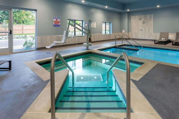 A pool area with clear steps leading into the water, a lifeguard chair, and a warning sign on the wall. - Baymont Inn & Suites by Wyndham Madison (Madison)