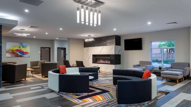 A modern lounge area with sofas, a fireplace, and a large window. - Baymont Inn & Suites by Wyndham Madison (Madison)