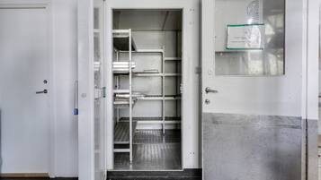 Une pièce propre, de style industriel, avec des étagères en métal et une porte dotée d’un panneau en verre dépoli.