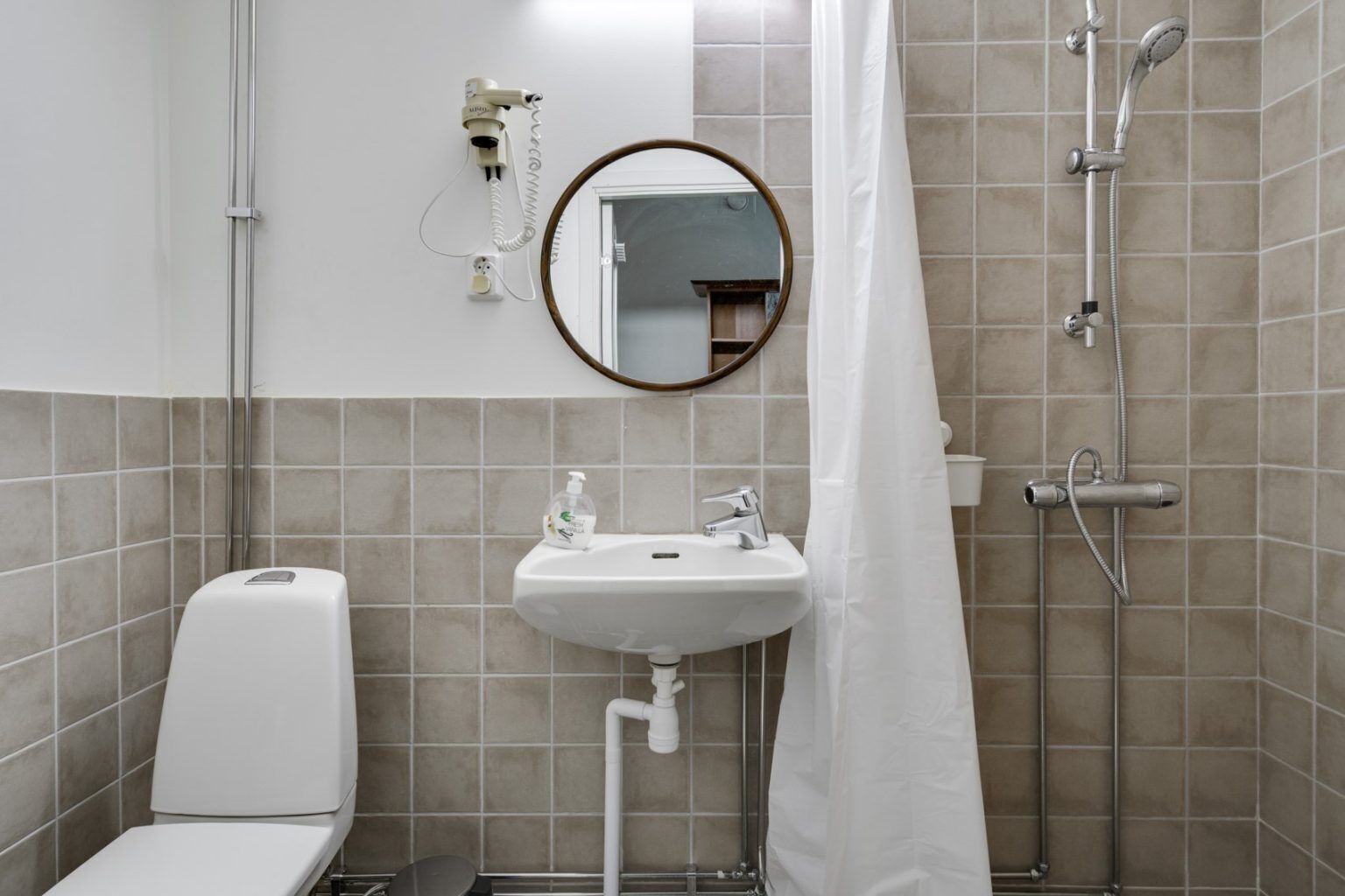 A bathroom with a toilet, sink, mirror, shower, and towel rack.