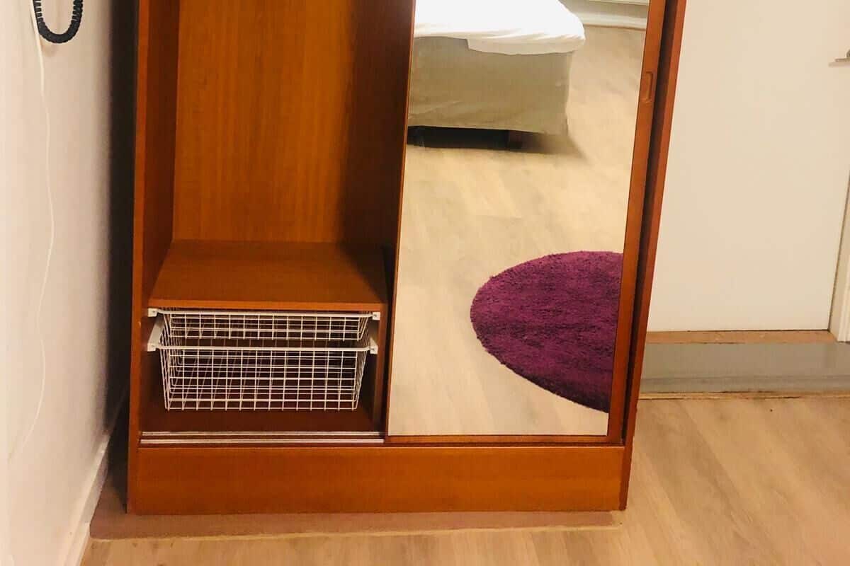 Una habitación con armario, cama, alfombra morada y teléfono.