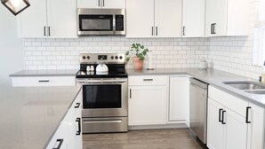 A modern kitchen with white cabinets, stainless steel appliances, and a wooden floor. - Peaceful park-like Getaway (Richland)