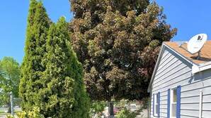 A well-maintained front yard with a lawn, a bench, and a house with satellite dishes. - Peaceful park-like Getaway (Richland)