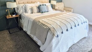 A bed with a quilted headboard, two bedside lamps, and a bedside table with a clock. - Peaceful park-like Getaway (Richland)