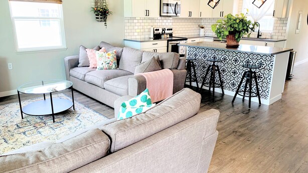A modern kitchen with white cabinets, stainless steel appliances, and a bar area with stools. - Peaceful park-like Getaway (Richland)