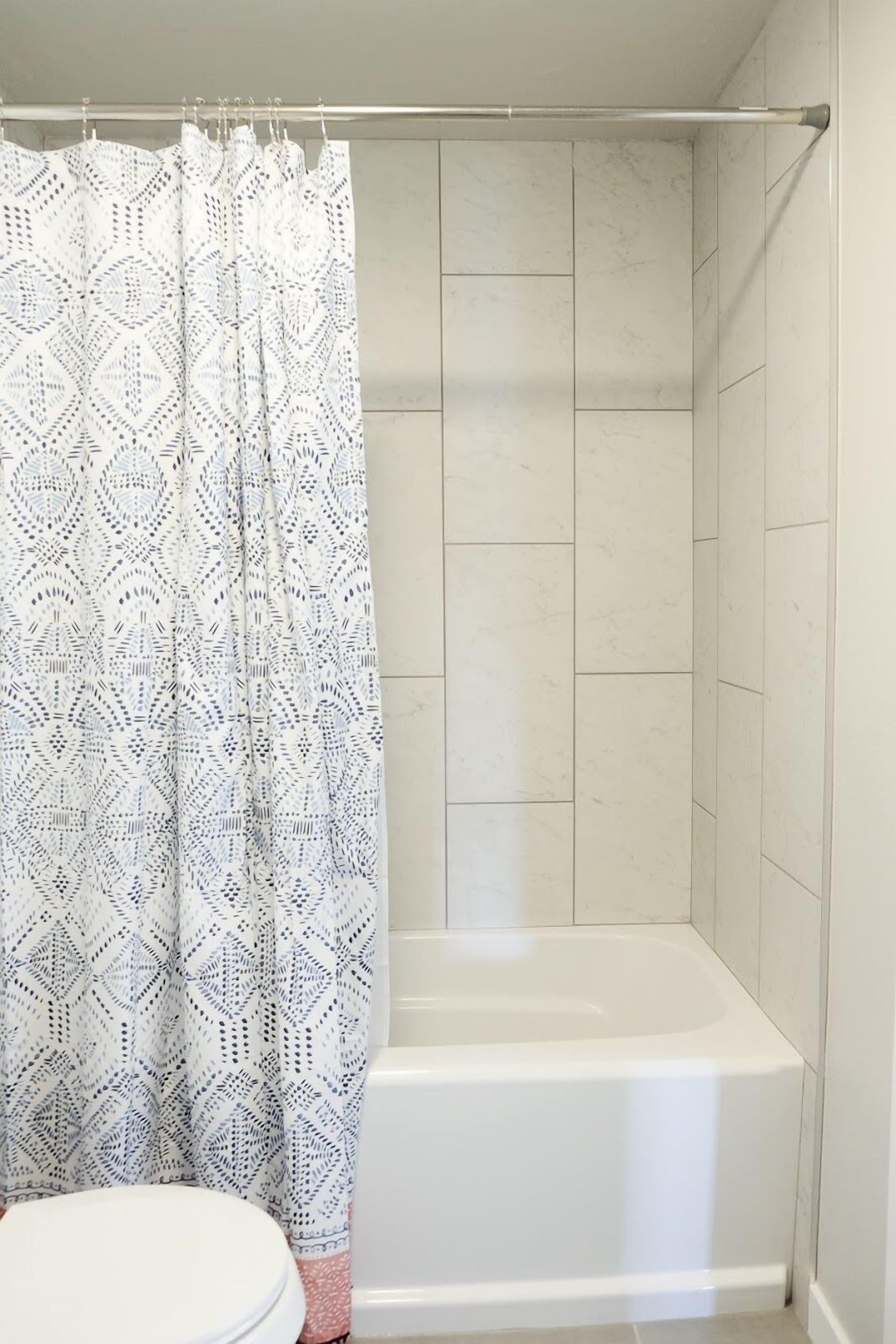 A bathroom with a shower curtain, a bathtub, and a toilet.