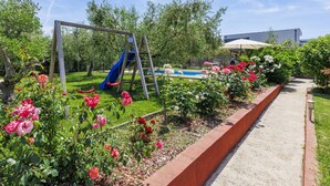 A playground with a swing set and slide, surrounded by a garden with roses and a pool. - Apartment Chiara by Interhome (Novigrad (Istra))