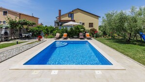 A swimming pool with lounge chairs and a barbecue area, surrounded by a well-maintained garden and a large house. - Apartment Chiara by Interhome (Novigrad (Istra))