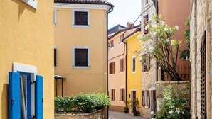 A narrow street with buildings on either side, featuring a stone wall and a small garden area. - Apartment Chiara by Interhome (Novigrad (Istra))