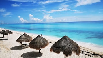 Pantai pribadi, pasir putih, payung pantai, dan handuk pantai