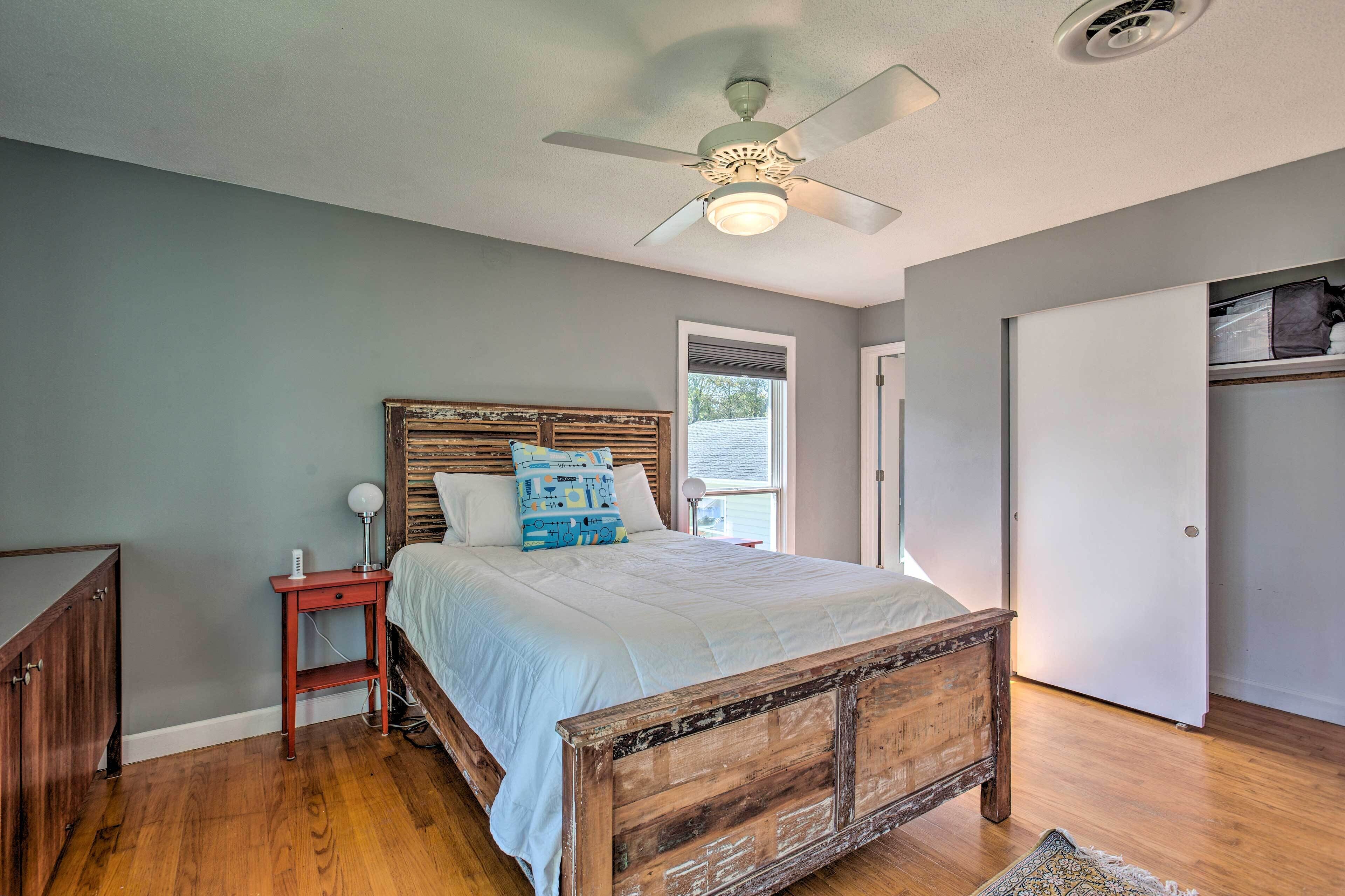 A bedroom with a wooden bed, a nightstand, a ceiling fan, and a window.