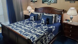 Un dormitorio ordenado con una cama grande, una mesita de noche, una lámpara y un reloj de pared.