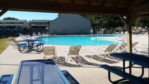 Un área de piscina con sillones de descanso y una zona de estar cubierta.
