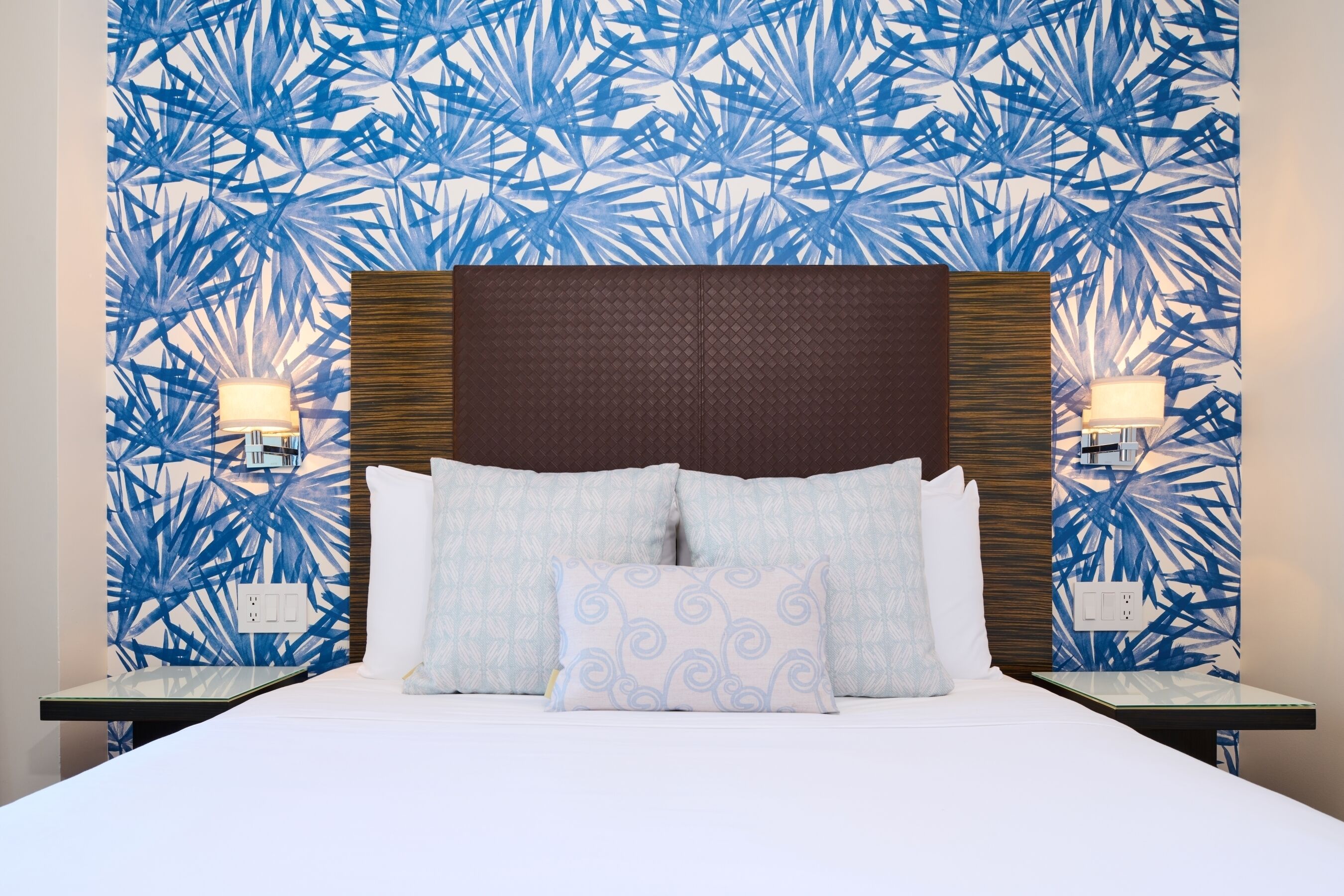 Une chambre d’hôtel avec un lit, deux tables de chevet et des appliques murales.