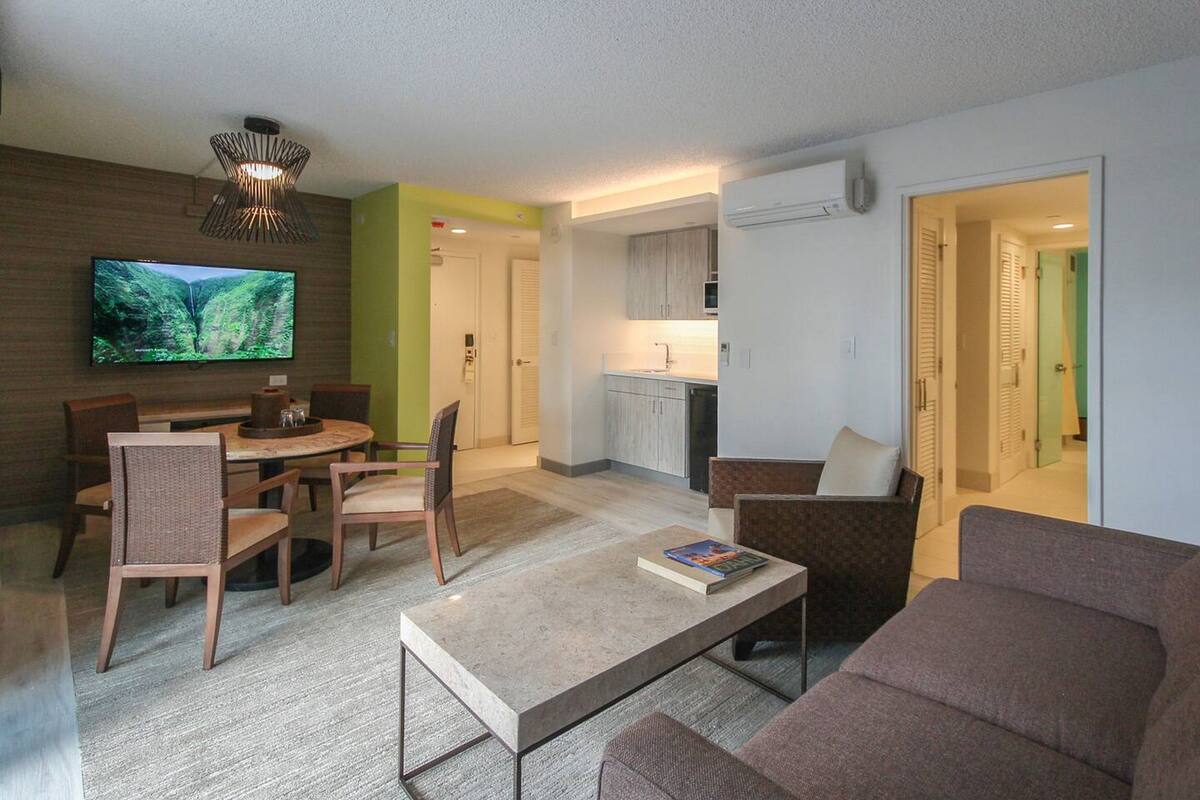 Una sala de estar moderna con televisor, comedor y cocina.