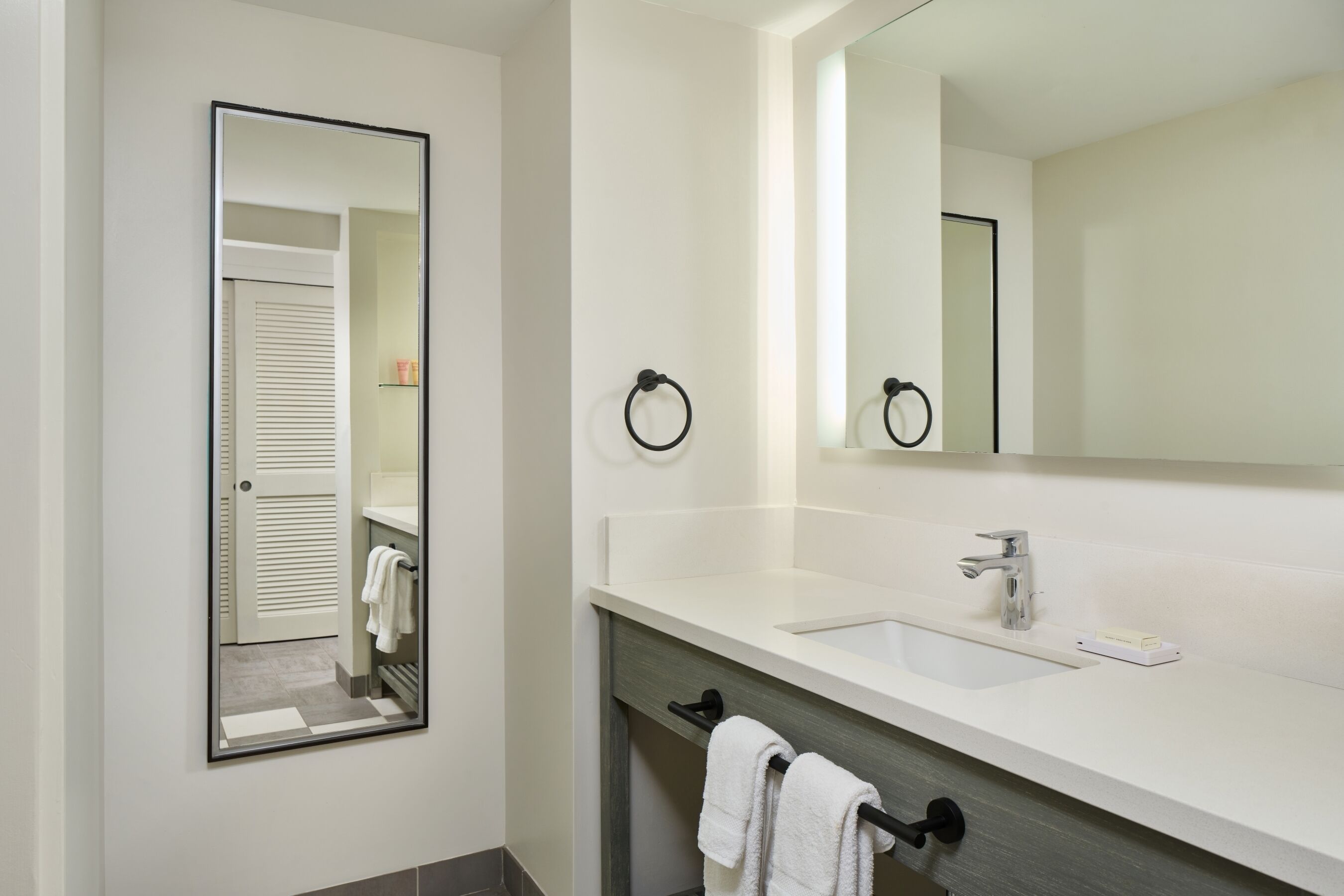 Un baño moderno con un espejo grande, un lavabo y un perchero para toallas.