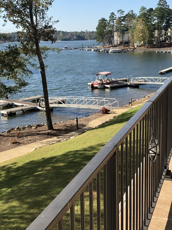 A lakeside view with a dock, boats, and a grassy area.