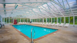 An indoor swimming pool with a glass ceiling, surrounded by lounge chairs and a Coca-Cola cooler. - Location, location, location! 2br/2bath condo in the heart of Pigeon Forge (Pigeon Forge)