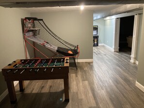 Una habitación con mesa de fútbol de mesa, aro de baloncesto y consola Nintendo Wii.
