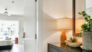 Um banheiro moderno com toucador escuro, espelho, luminária e planta em vaso.
