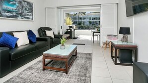 Uma sala de estar moderna com um sofá de couro preto, uma mesa de centro de vidro e um ventilador de teto.