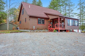 A two-story wooden cabin with a red roof and a porch. - Gorgeous Lakefront Home with a Fire Pit, Two Living Areas, and a Sunroom (Chestertown)