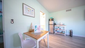 A modern kitchen with a wooden table and white chairs, a refrigerator, and a microwave. - Centrally Located Charming Beach Suite in Sarasota (Sarasota)