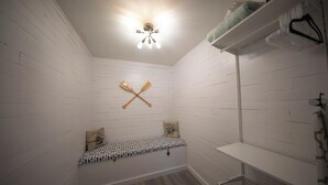A small, white-walled room with a bench, a ceiling light fixture, and a shelf with folded clothes. - Centrally Located Charming Beach Suite in Sarasota (Sarasota)