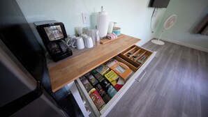 A kitchen area with a coffee maker, mugs, and a drawer with various food items. - Centrally Located Charming Beach Suite in Sarasota (Sarasota)