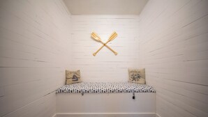 A small, cozy room with a bench and two pillows, a wooden wall, and a ceiling with two crossed paddles. - Centrally Located Charming Beach Suite in Sarasota (Sarasota)