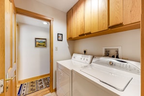 Laundry room with washer and dryer, cabinetry, and a door leading to another room.
