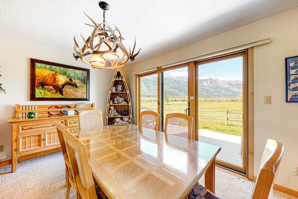 Enjoy meals in this dining area with a large table and comfortable chairs, surrounded by a scenic view of the mountains.