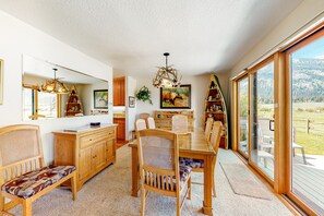 Enjoy meals in this dining area with a large table and six chairs, surrounded by a high ceiling and a unique chandelier.