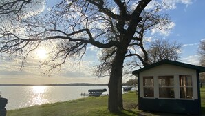 A lakeside cabin with a large tree in the foreground, a dock, and a boat in the background. - Enjoy Lake Life, A Great Minnesota Getaway! (Henning)