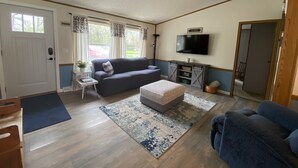 A compact living space with a sofa, ottoman, and a television mounted on the wall. - Enjoy Lake Life, A Great Minnesota Getaway! (Henning)