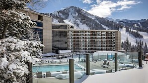 Ein Hotel mit Poolbereich, umgeben von schneebedeckten Bergen und Bäumen.