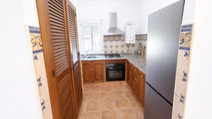 A compact kitchen with a built-in oven, a refrigerator, and a gas stove. - Chalet rustic Roche with pool (CONIL DE LA FRONTERA)