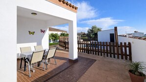 A patio with a table and chairs, a wooden fence, and a potted plant. - Chalet rustic Roche with pool (CONIL DE LA FRONTERA)