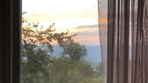 Ein Fenster mit Blick auf Bäume und einen Sonnenuntergang.