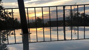 Ein Sonnenuntergang über ruhigem Wasser, im Vordergrund eine Metallreling.