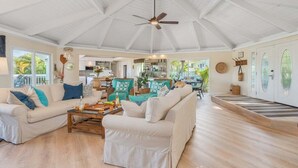 A spacious living room with a high ceiling and a ceiling fan, furnished with a beige sofa and a coffee table.