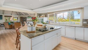 A modern kitchen with a large island, white cabinetry, and a view of the outdoors.