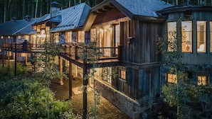 Una baita di legno con un camino in pietra, ampie finestre e una veranda.