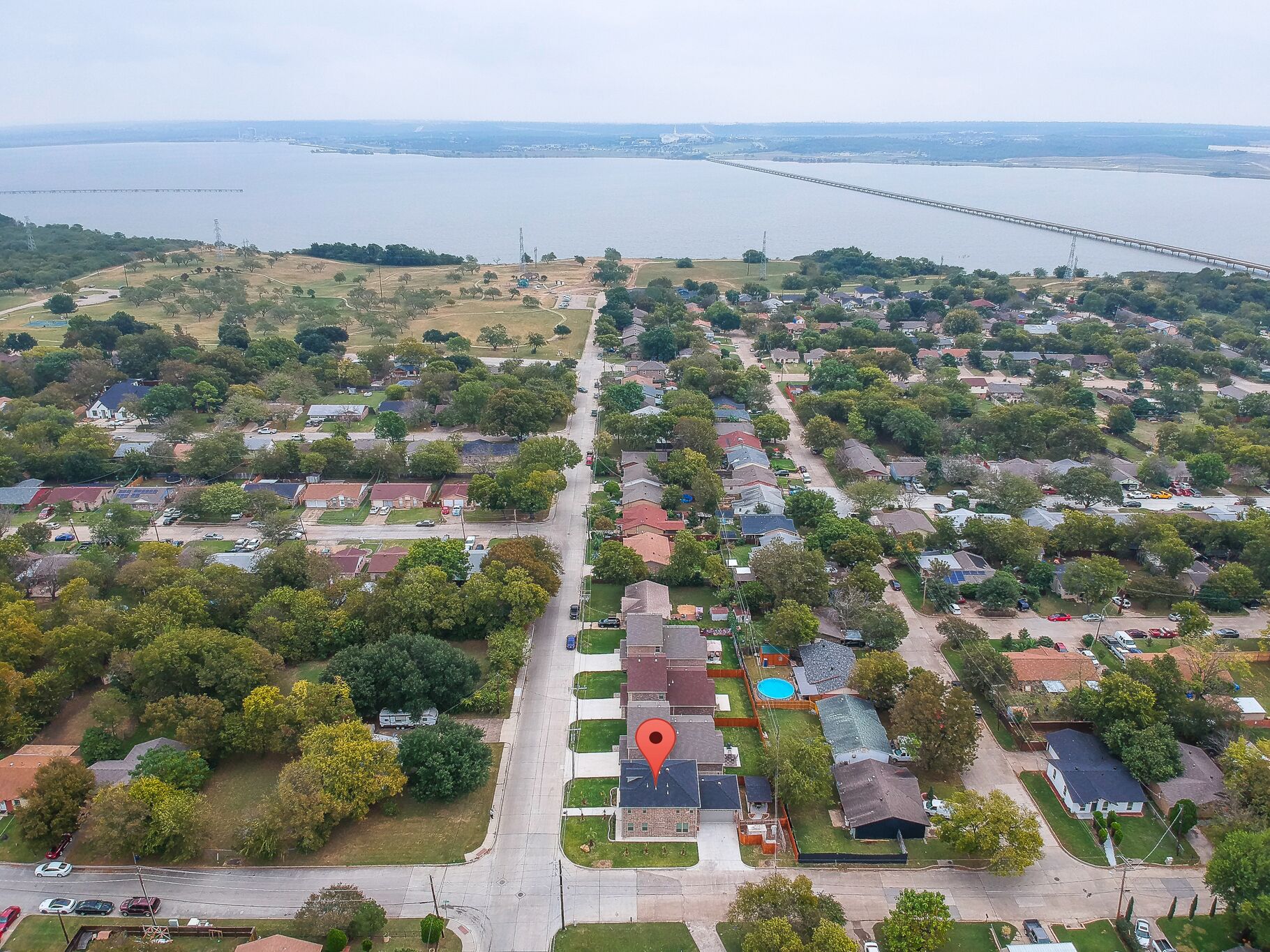 Vue aérienne d’un quartier résidentiel avec des maisons, une route et un pont en arrière-plan.