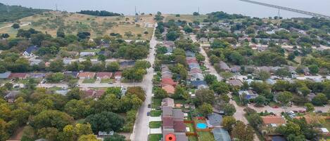 Vue aérienne d’un quartier résidentiel avec des maisons, une route et un pont en arrière-plan.