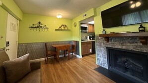 Ein gemütliches Wohnzimmer mit Kamin, Essbereich und Küche mit einer Wand aus Naturstein.