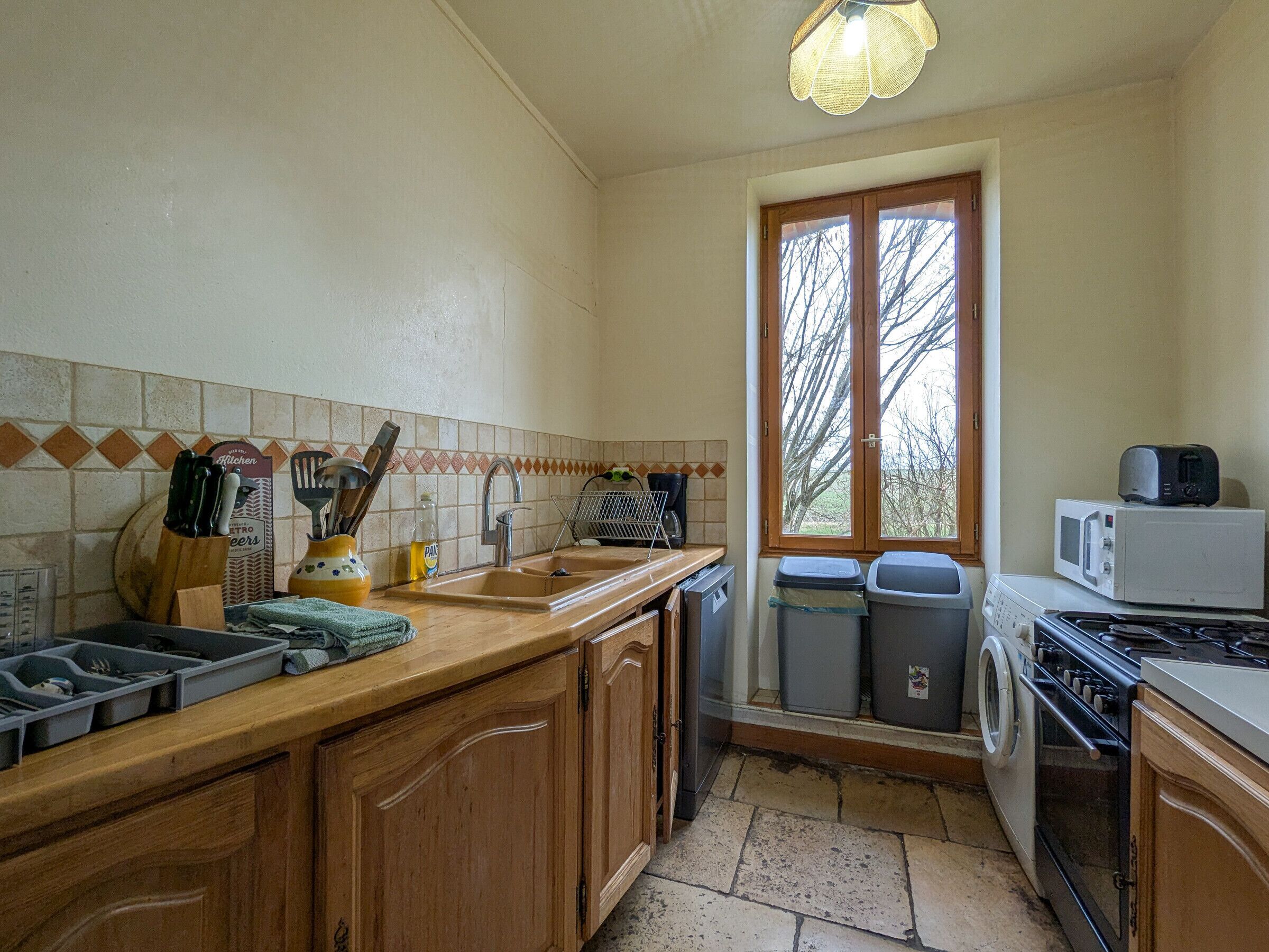 A compact kitchen with wooden cabinets, a sink, a stove, and a microwave.